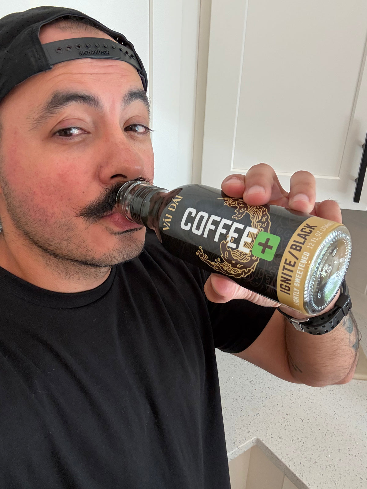 A man with a mustache taking a sip of his Vai Dai Black.