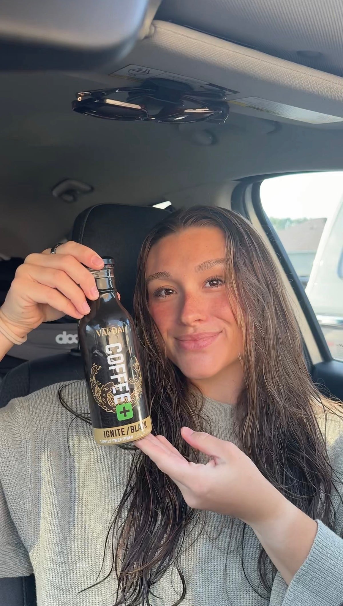 Woman holding a Vai Dai Black bottle in her car